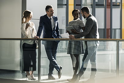 group of young businesspeople standing chatting on office balcony