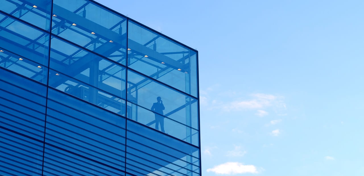 Exterior view of a businessman standing alone in the corner of office building.