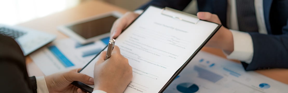 Business owner reviewing insurance documents with an advisor while discussing business liability insurance coverage options.