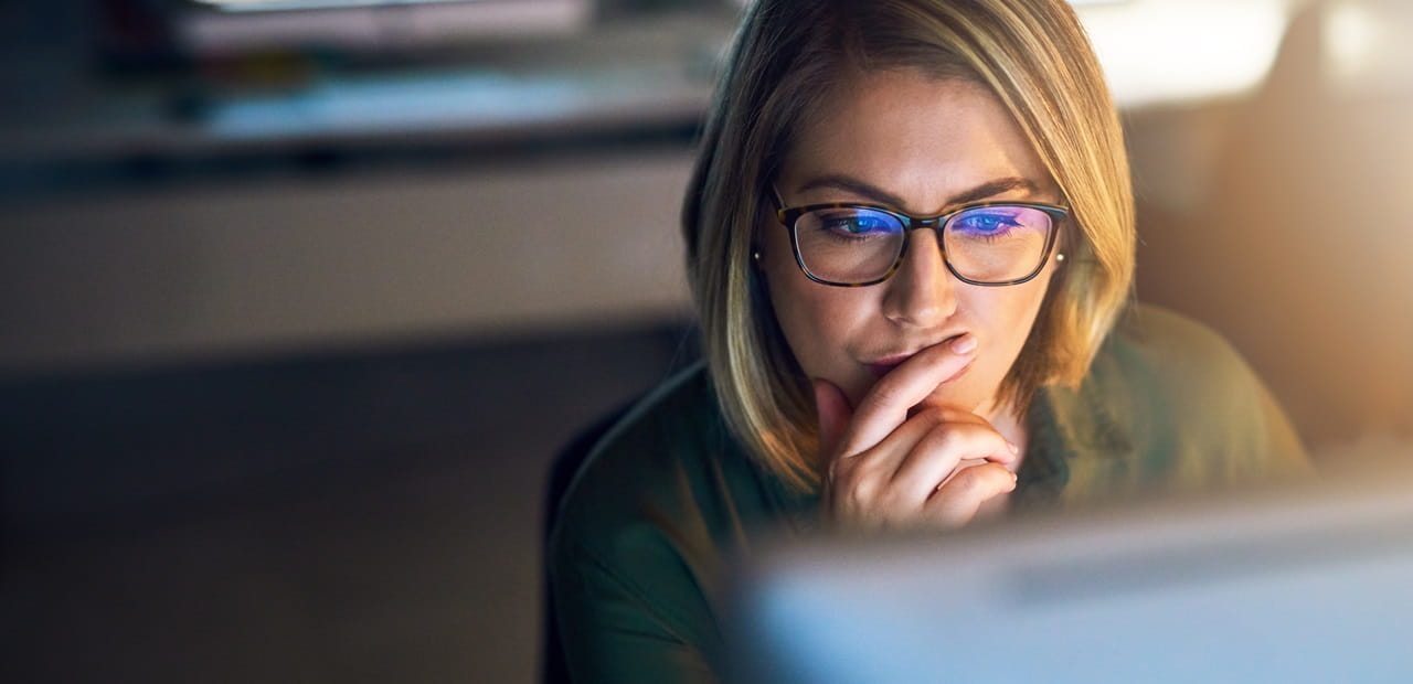 Woman wearing glasses focusing on a computer screen.
