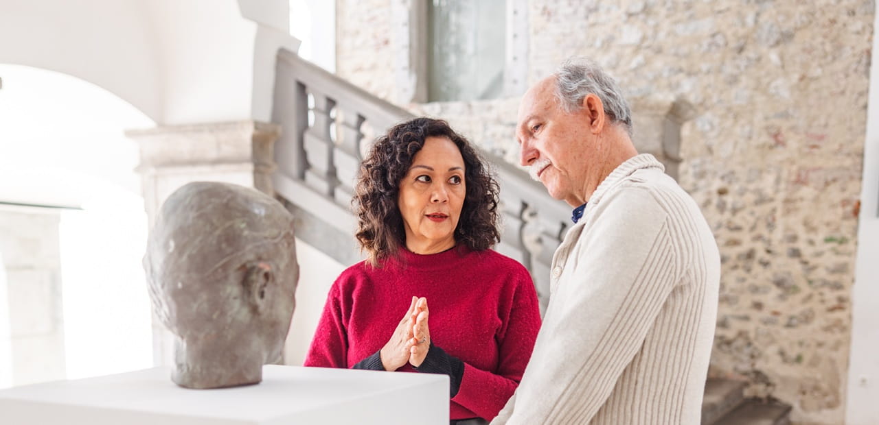 Museum docent guiding a visitor through an exhibit, illustrating how service, creativity, and connection can bring purpose later in life.