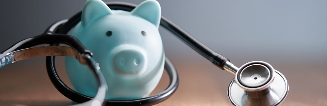 Piggy bank wrapped with a stethoscope on a table, representing Medicare costs and the importance of understanding common misconceptions when planning for health care expenses in retirement.