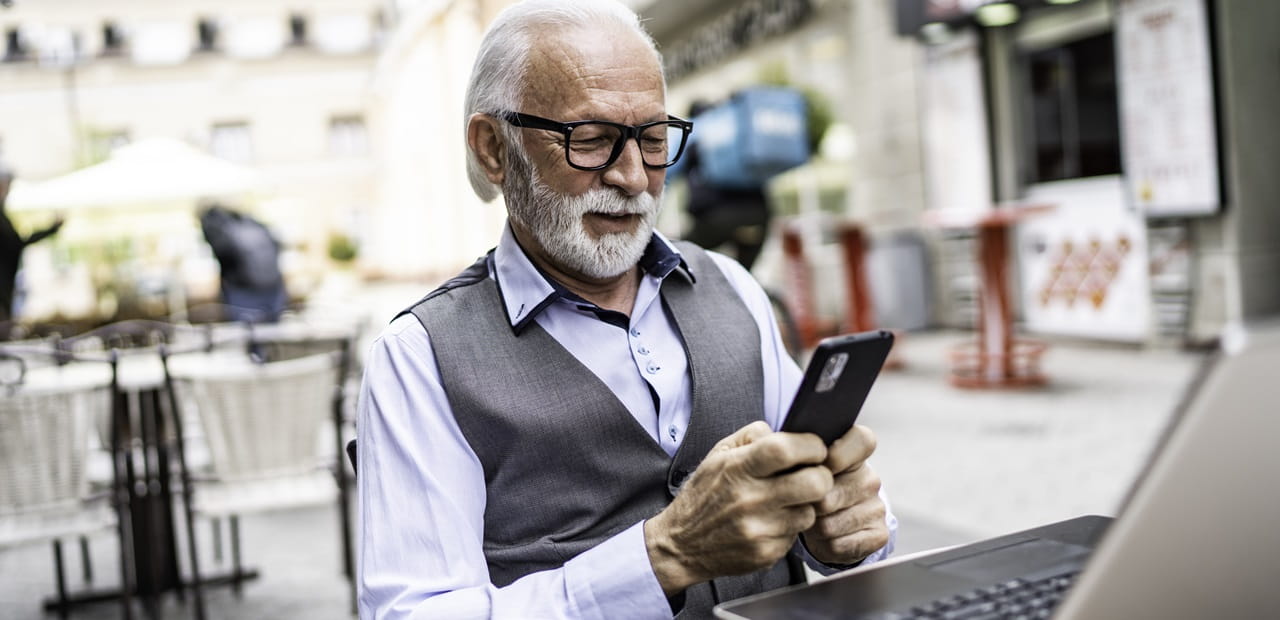 Senior businessman in a cafe looking at his smart phone.