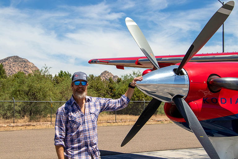 Fernando Campoo with his hand on the chrome propeller of a red plane
